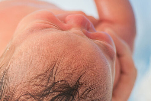 Neugeborenes kurz nach der Geburt in den Händen der Hebamme