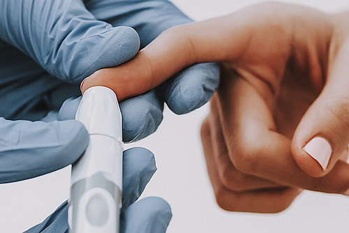 Arzt nimmt Blutporbe aus Zeigefinger einer Diabetes-Patientin