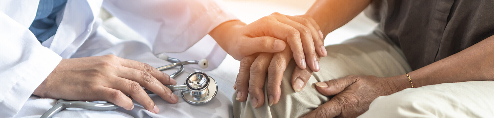 Arzt hält Hand eines Parkinson-Patienten