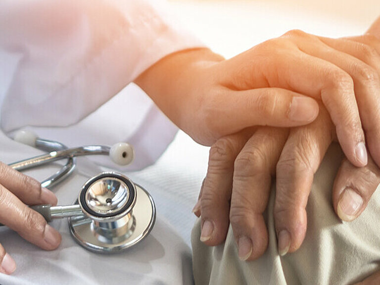 Arzt hält Hand eines Parkinson-Patienten
