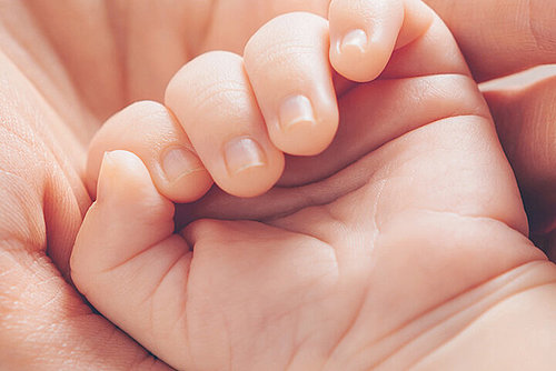Mutter hält kleine Hand ihres Neugeborenes
