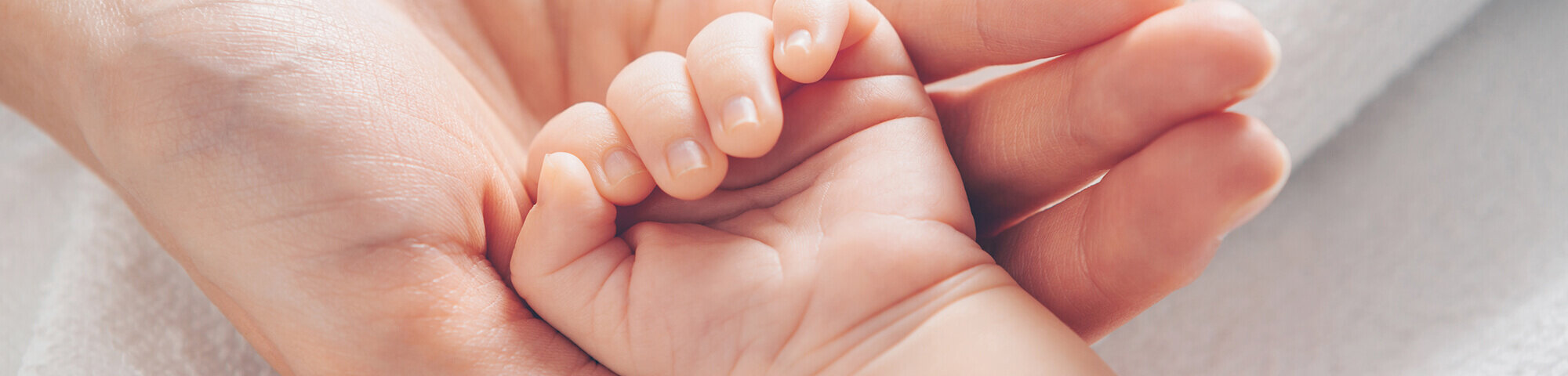 Mutter hält kleine Hand ihres Neugeborenes